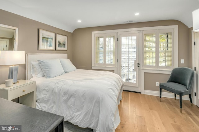 bedroom with light wood-type flooring, vaulted ceiling, and multiple windows