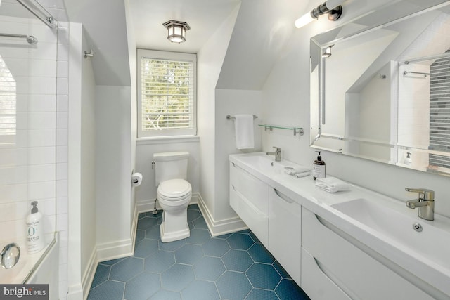 full bath with double vanity, baseboards, toilet, vaulted ceiling, and a sink