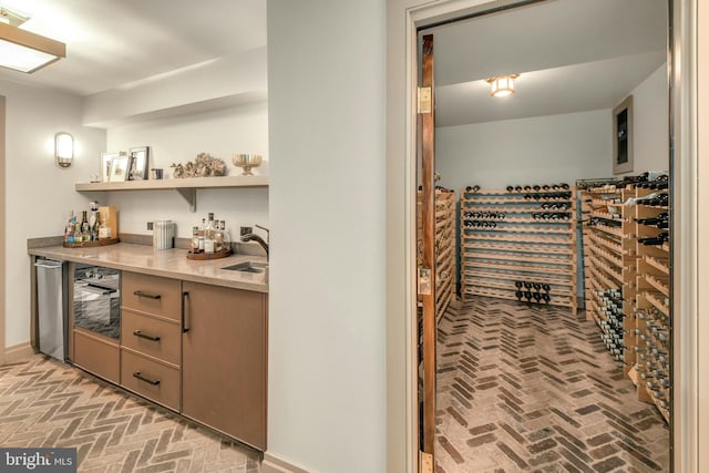 bar with a dry bar, brick floor, baseboards, and a sink