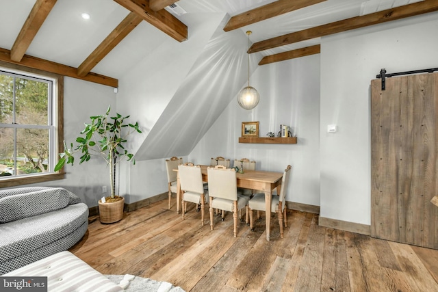 dining area featuring vaulted ceiling with beams, light hardwood / wood-style flooring, and a barn door