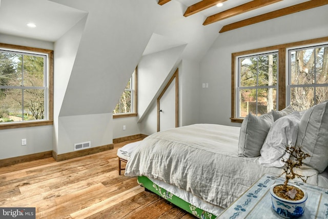 bedroom with lofted ceiling with beams, hardwood / wood-style flooring, and multiple windows