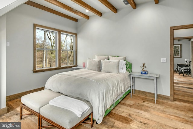 bedroom featuring beamed ceiling and light hardwood / wood-style floors