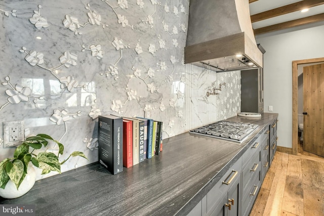 kitchen featuring dark countertops, premium range hood, stainless steel gas cooktop, and gray cabinetry