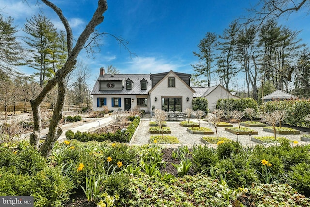 back of property with a chimney, a vegetable garden, and fence