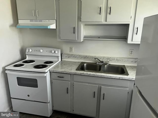 kitchen featuring white electric range, gray cabinets, dark tile flooring, stainless steel fridge, and sink