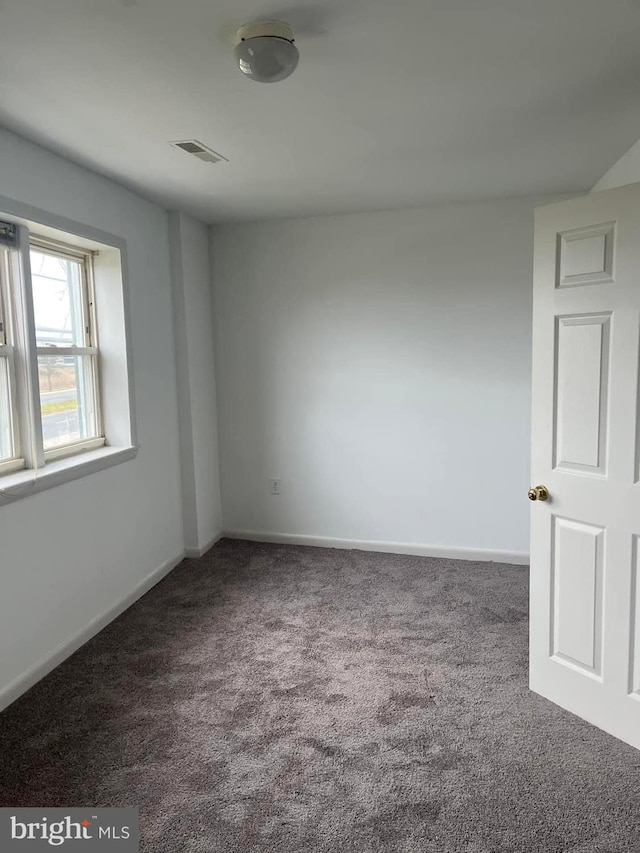 unfurnished room with dark colored carpet