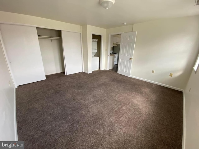 unfurnished bedroom with a closet and dark colored carpet