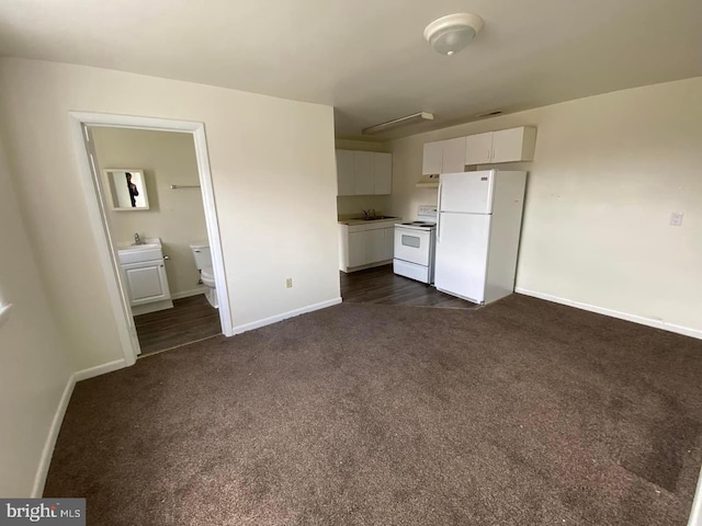 unfurnished bedroom with dark carpet, ensuite bath, sink, and white refrigerator