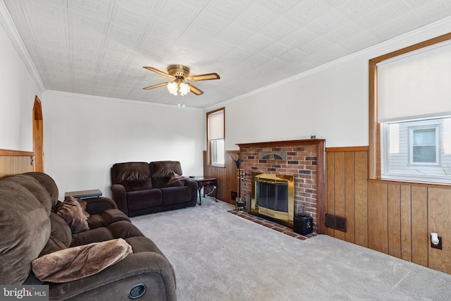 living room featuring crown molding, ceiling fan, light colored carpet, and a brick fireplace