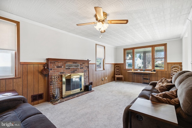 living room featuring wood walls, ornamental molding, a wealth of natural light, and a brick fireplace