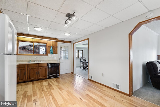 kitchen with a paneled ceiling, light hardwood / wood-style floors, dishwasher, sink, and white refrigerator