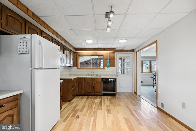 kitchen with white appliances, sink, light wood-type flooring, a drop ceiling, and tasteful backsplash