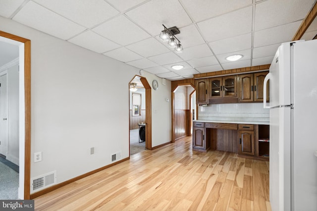 kitchen featuring white fridge, a drop ceiling, tasteful backsplash, and light hardwood / wood-style floors