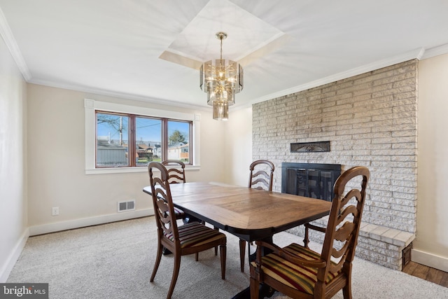 dining area featuring ornamental molding, a notable chandelier, light carpet, and a fireplace