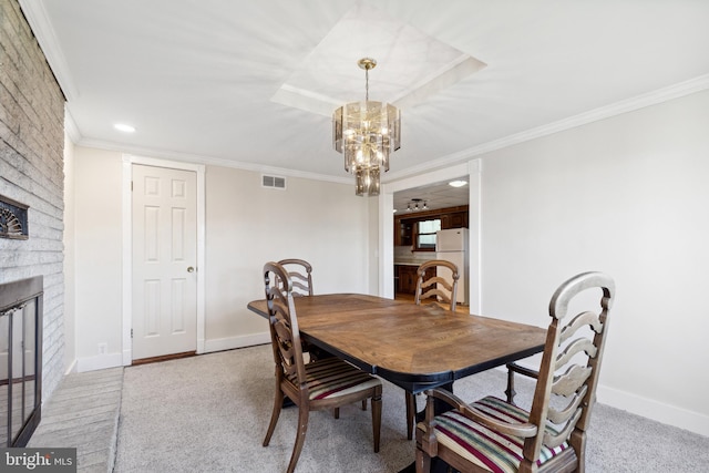 dining space with a brick fireplace, ornamental molding, light colored carpet, and a chandelier