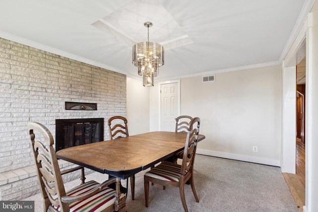 dining area with an inviting chandelier, a brick fireplace, ornamental molding, and light colored carpet