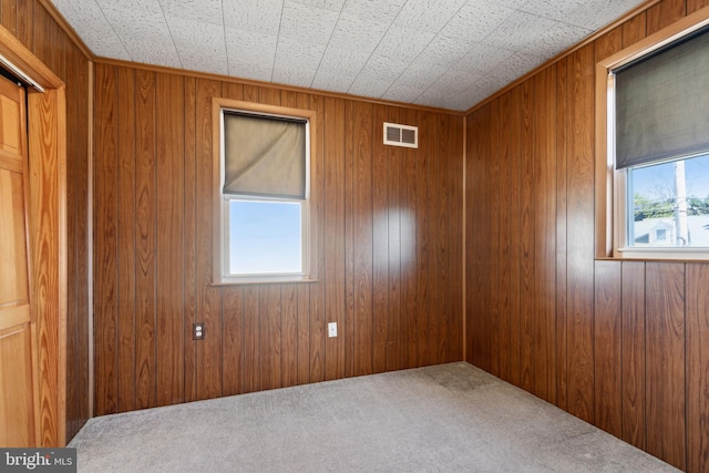 unfurnished room featuring carpet floors and wooden walls