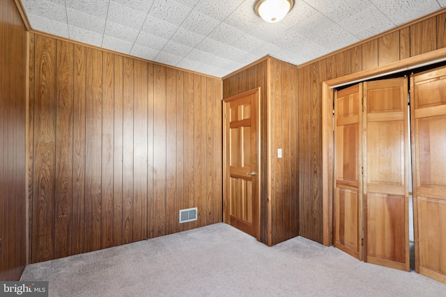 unfurnished bedroom with wood walls and light carpet