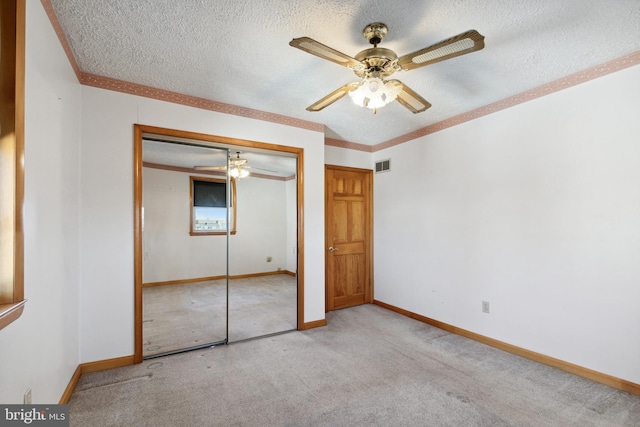 unfurnished bedroom with ceiling fan, a closet, light carpet, and a textured ceiling