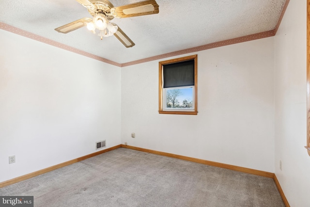 spare room with ceiling fan, a textured ceiling, light colored carpet, and crown molding