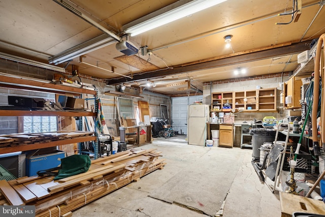 garage featuring a workshop area, white refrigerator, and a garage door opener