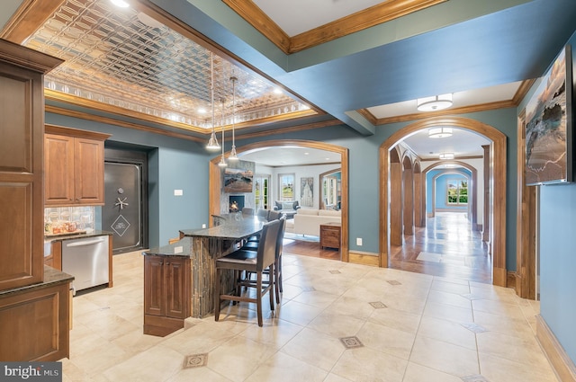 kitchen featuring dishwasher, a kitchen bar, crown molding, and dark stone counters