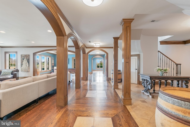 foyer with hardwood / wood-style flooring, ornate columns, and crown molding