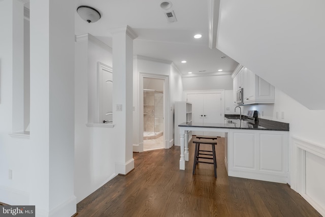 kitchen featuring kitchen peninsula, white cabinetry, dark hardwood / wood-style flooring, and crown molding