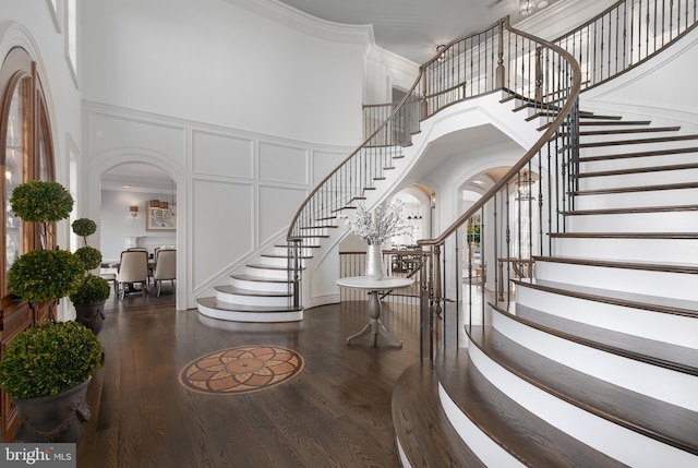 entryway with dark hardwood / wood-style floors, a towering ceiling, and ornamental molding