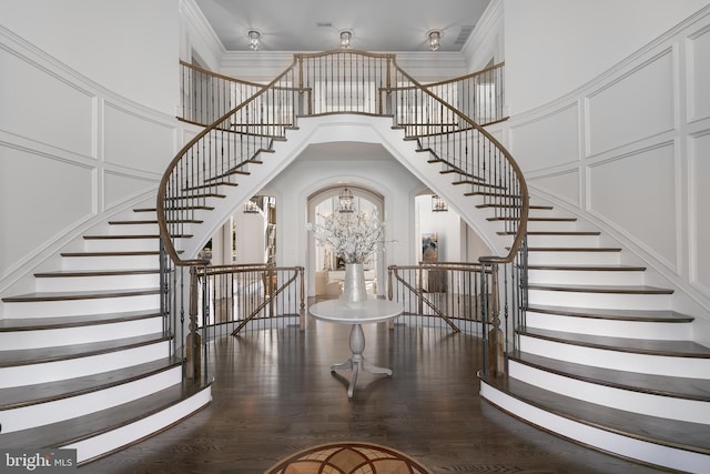 entryway with a towering ceiling, ornamental molding, and hardwood / wood-style flooring