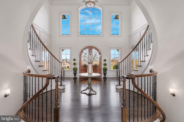 entryway featuring an inviting chandelier, a high ceiling, dark hardwood / wood-style floors, and ornamental molding