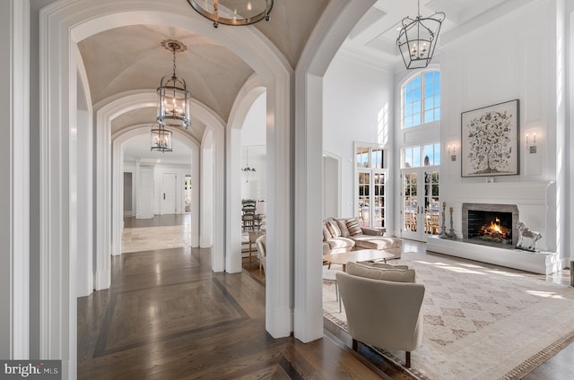 corridor featuring dark parquet floors, ornamental molding, and a high ceiling