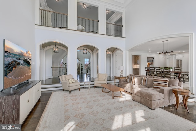 living room with a chandelier, a towering ceiling, hardwood / wood-style flooring, and ornamental molding