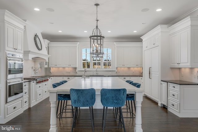 kitchen with stainless steel appliances, white cabinetry, dark wood-type flooring, and crown molding