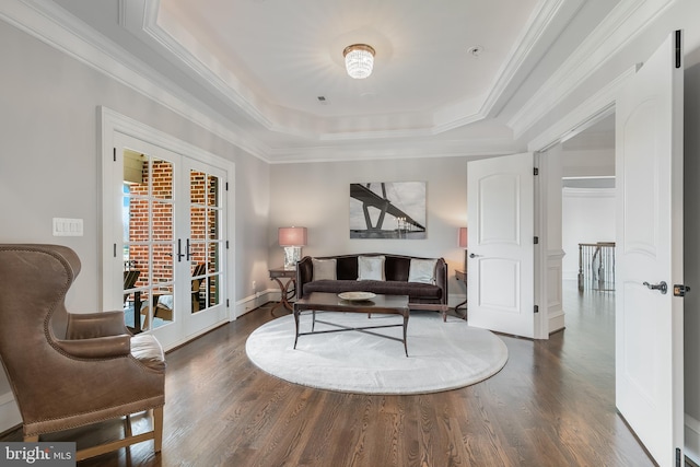 living room featuring french doors, a tray ceiling, crown molding, and dark wood-type flooring