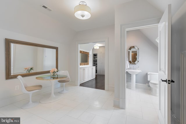 hallway featuring light tile patterned floors and lofted ceiling