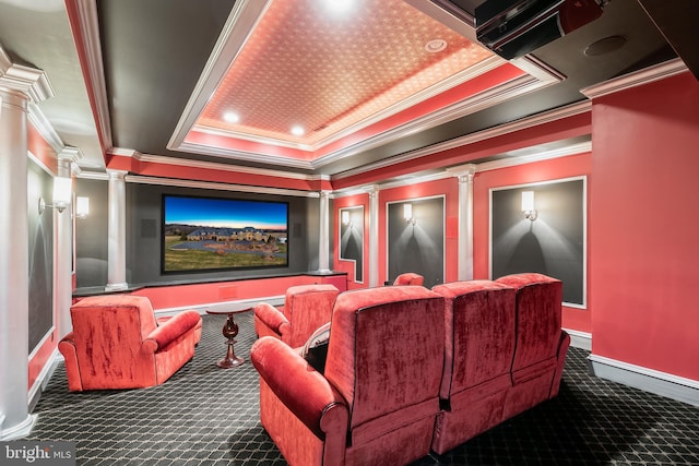 home theater room with decorative columns, a raised ceiling, crown molding, and dark carpet