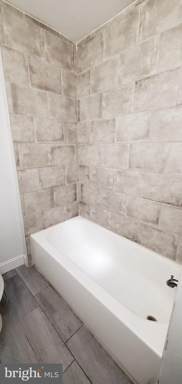 bathroom featuring tiled shower / bath, tile walls, and wood-type flooring