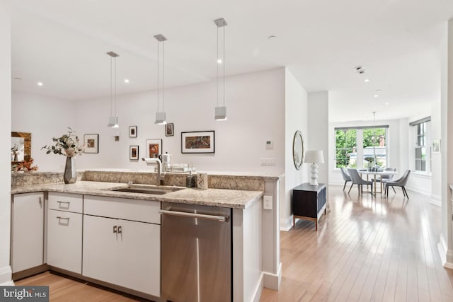 kitchen featuring light hardwood / wood-style floors, light stone countertops, white cabinets, pendant lighting, and dishwasher