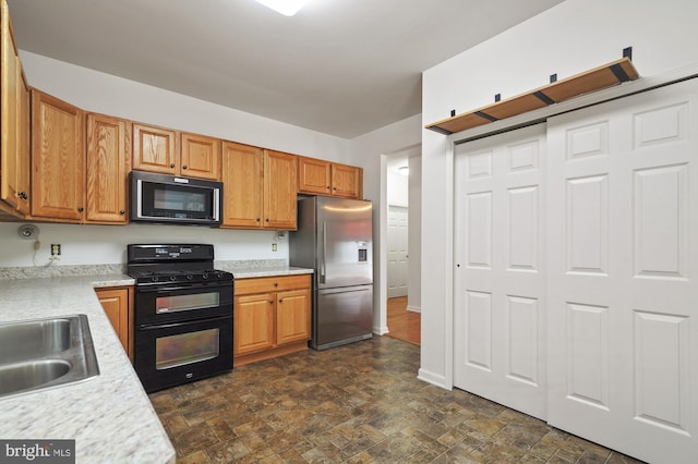 kitchen featuring dark tile floors, sink, and black appliances