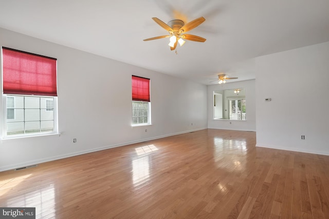 spare room with light wood-type flooring, ceiling fan, and a healthy amount of sunlight