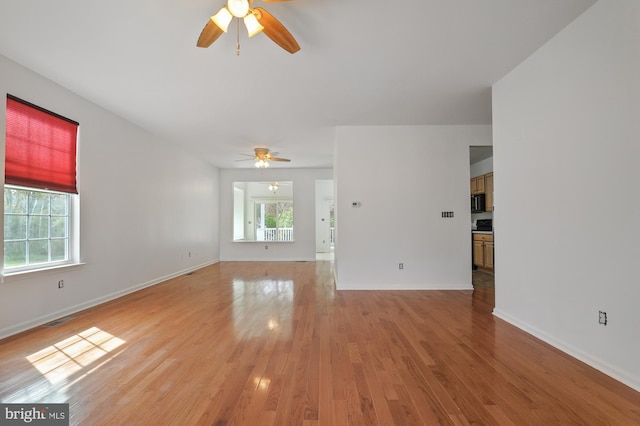 unfurnished living room featuring a wealth of natural light, ceiling fan, and light wood-type flooring