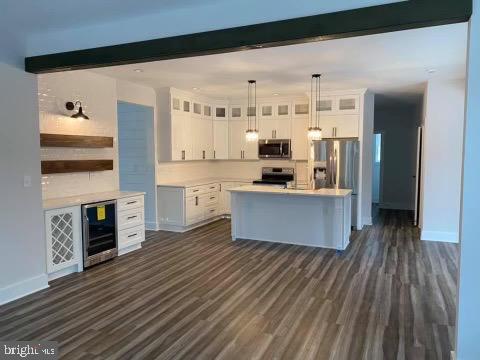 kitchen with beamed ceiling, white cabinets, and appliances with stainless steel finishes