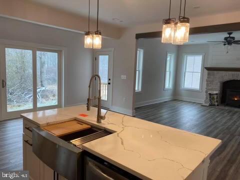 kitchen featuring dark wood-type flooring, pendant lighting, an island with sink, and a healthy amount of sunlight