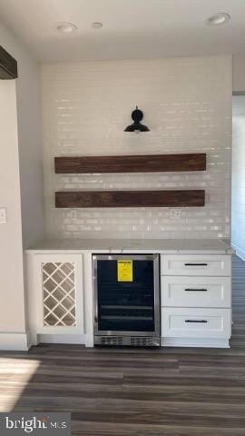 bar with dark hardwood / wood-style floors, white cabinetry, and beverage cooler