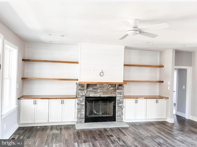 unfurnished living room featuring a fireplace, dark hardwood / wood-style floors, and ceiling fan