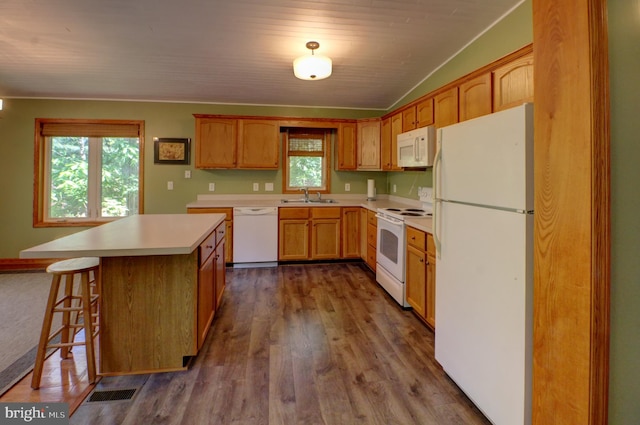 kitchen featuring a wealth of natural light, white appliances, sink, and a center island