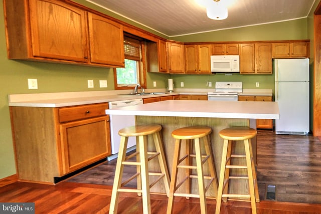 kitchen with dark wood-type flooring, a center island, vaulted ceiling, a breakfast bar, and white appliances