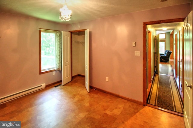 unfurnished room with an inviting chandelier and a baseboard heating unit