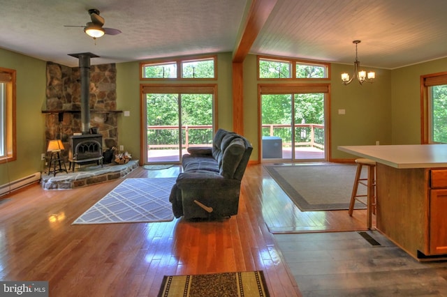 living room featuring a wood stove, light wood-type flooring, plenty of natural light, and vaulted ceiling with beams